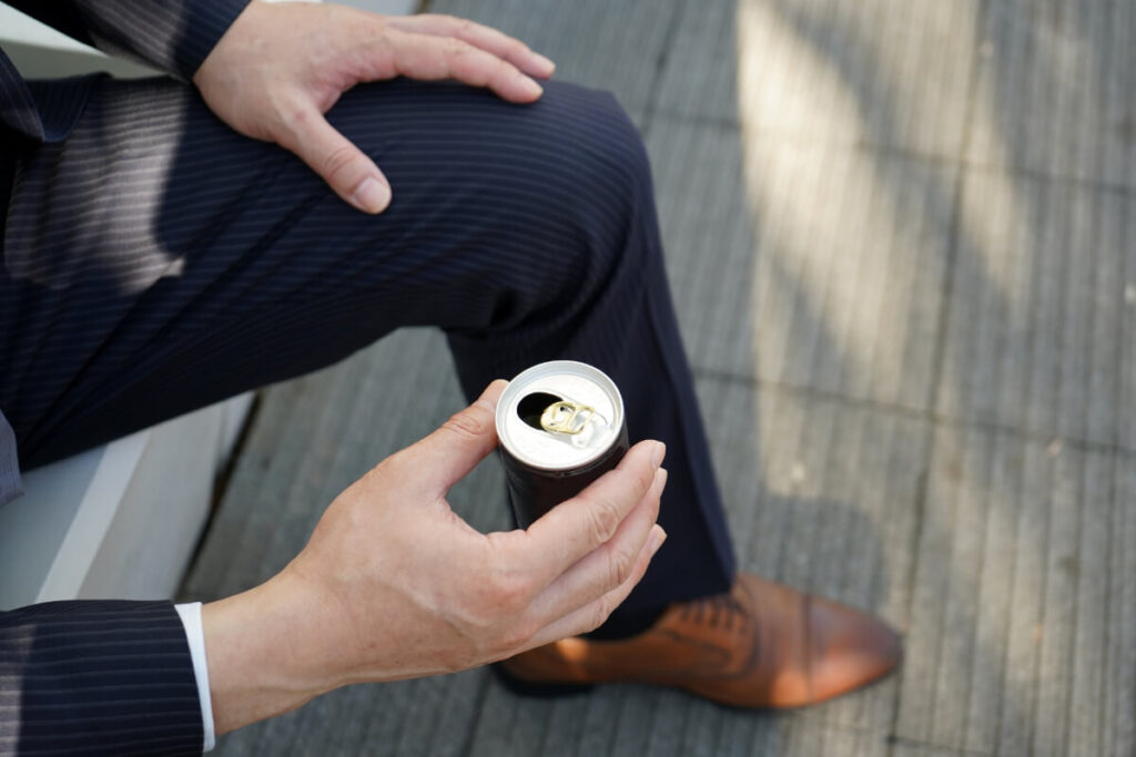 「缶コーヒーを飲むスーツを着た男性」のイメージ画像