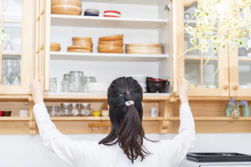 「食器棚を開く女性の後ろ姿」のイメージ画像